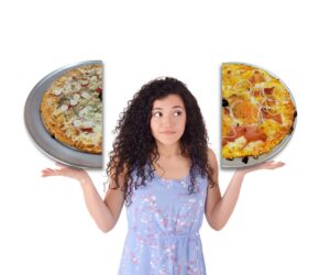 Chica sujetando dos mitades de pizza, cada una de una tipología diferente.